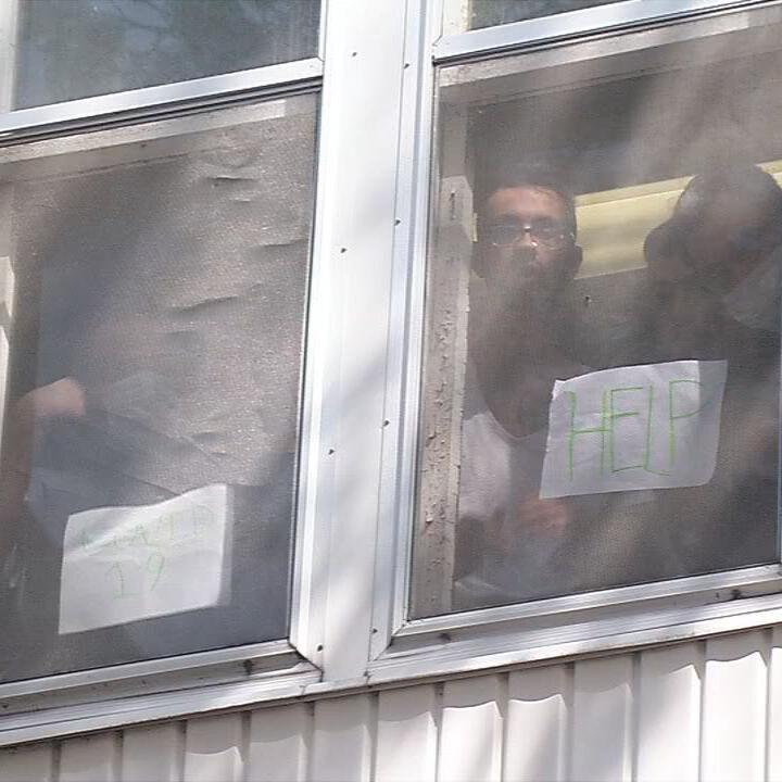 Residents of Dismass Charaties - St. Ann's halfway house hold up signs asking for help